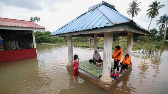 A family is seen sitting in a pergola surrounded by floodwaters in Pasir Mas, Kelantan, on December 21. Malaysia's meteorological department forecast continuous rains through December 22 in several states, including Terengganu.&nbsp;(AFP)