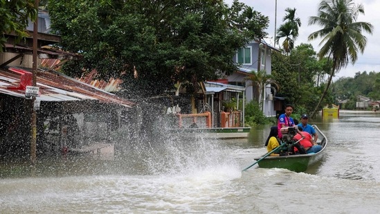 Local residents are seen using a boat to cross flooded streets in Pasir Mas, Kelantan, on December 21. Authorities have urged residents to evacuate, wherever possible.&nbsp;(AFP)