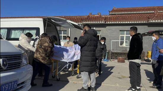 Workers unload a body from a vehicle for cremation at Gaobeidian Funeral Home in northern China's Hebei province, on Thursday. China only counts deaths from pneumonia or respiratory failure in its official Covid-19 death toll, a health official said, a narrow definition that limits the number of deaths being reported as the virus surges following the easing of pandemic-related restrictions. (AP)