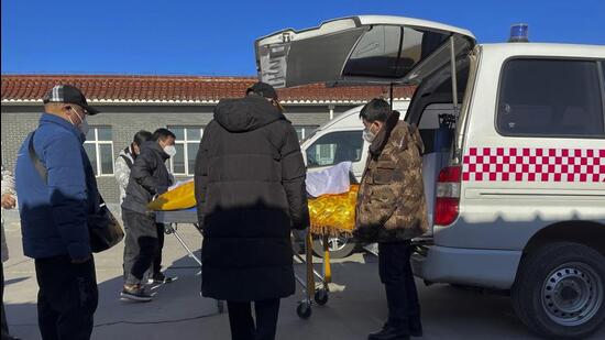 Workers unload a body from an ambulance for cremation at Gaobeidian Funeral Home in northern China’s Hebei province, on Thursday. China only counts deaths from pneumonia or respiratory failure in its official Covid-19 death toll, a health official said. (AP)