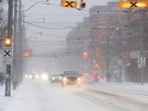 Cars drive through blowing snow during a snowstorm in Toronto, Canada on Friday. In US, a 50-vehicle pileup on the Ohio Turnpike in a blizzard near Toledo killed two motorists, and injured numerous others.(AP)