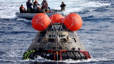 NASA's Orion capsule is drawn to the well deck of the U.S.S. Portland after it splashed down following a successful uncrewed Artemis I Moon Mission. (Mario Tama / REUTERS)