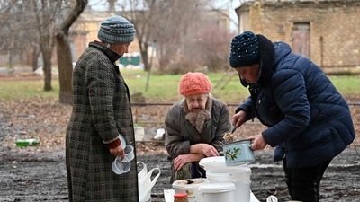 TOPSHOT - A local resident distributes to her neighbours hot food brought by volunteers in the yard of a residential building in the de-occupied town of Izyum, Kharkiv region on December 22, 2022, amid the Russian invasion of Ukraine. (Photo by SERGEY BOBOK / AFP) TOPSHOT - A local resident distributes to her neighbours hot food brought by volunteers in the yard of a residential building in the de-occupied town of Izyum, Kharkiv region on December 22, 2022, amid the Russian invasion of Ukraine. (Photo by SERGEY BOBOK / AFP)