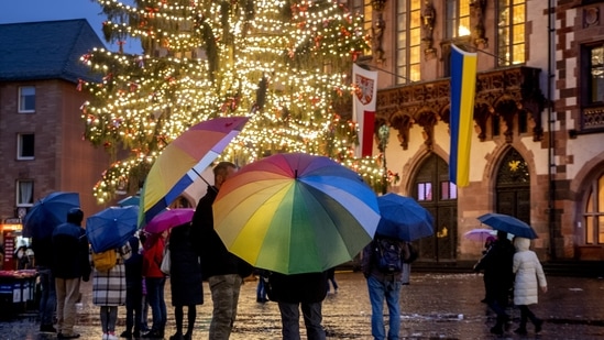People with umbrellas are seen standing at the Roemerberg square on a rainy day with a Christmas tree in Frankfurt, on December 23.&nbsp;(Michael Probst / AP)