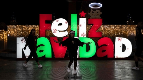 Dancers are seen performing in front of a Merry Christmas sign on the eve of the Christmas celebration on Los Proceres boulevard in Caracas on December 23.(Yuri Cortez / AFP)