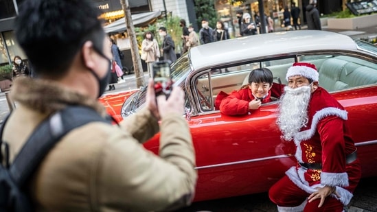 Member of the vintage car group Hiroyuki Wada, dressed as Santa Claus, poses with a child in his 1959 Cadillac in Hibiya district of Tokyo on December 24.(Yuichi Yamazaki / AFP)