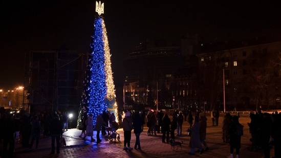 People gather around a Christmas tree decorated with the colors of the Ukrainian national flag at Sophia square in Kyiv, on December 23.&nbsp;(Felipe Dana / AP)