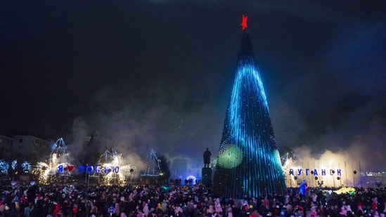 People are seen near the Christmas tree decorated for Christmas and the New Year festivities in Luhansk, on December 23.(AP)