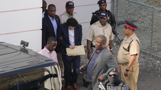 FTX founder Sam Bankman-Fried, center, is escorted out of Magistrate Court into a Corrections van, following a hearing in Nassau, Bahamas.(AP)