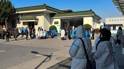 People wearing personal protective equipment stand outside a funeral home, as Covid-19 outbreak continues, in Shanghai, China on Saturday. (REUTERS) People wearing personal protective equipment stand outside a funeral home, as Covid-19 outbreak continues, in Shanghai, China on Saturday. (REUTERS)