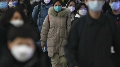 Covid In China: Masked commuters walk through a walkway in between two subway stations as they head to work. (AP) Covid In China: Masked commuters walk through a walkway in between two subway stations as they head to work. (AP)