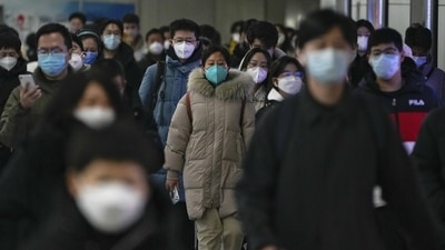 Covid In China: Masked commuters walk through a walkway in between two subway stations as they head to work. (AP) Covid In China: Masked commuters walk through a walkway in between two subway stations as they head to work. (AP)