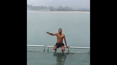The man, sitting on a railing in shorts, is offering people to take dips in the holy river on their behalf for a small fee. (Twitter/@AwanishSharan) The man, sitting on a railing in shorts, is offering people to take dips in the holy river on their behalf for a small fee. (Twitter/@AwanishSharan)