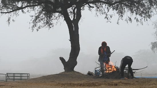 People huddle around a bonfire to warm themselves on a cold morning at Dwarka, in New Delhi, on December 24. On December 25, Delhi recorded the season’s first coldwave conditions taking both the maximum and minimum temperatures to this winter’s lowest so far, HT reported.(Vipin Kumar / HT Photo)