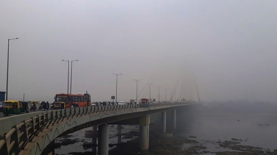 Vehicles ply on the Signature Bridge during a cold foggy morning, in New Delhi, on December 26. Prior to December 25, the lowest maximum temperature in Delhi had been 20 degrees Celsius, which was recorded on December 24, HT reported.(Sachin Saini / PTI)