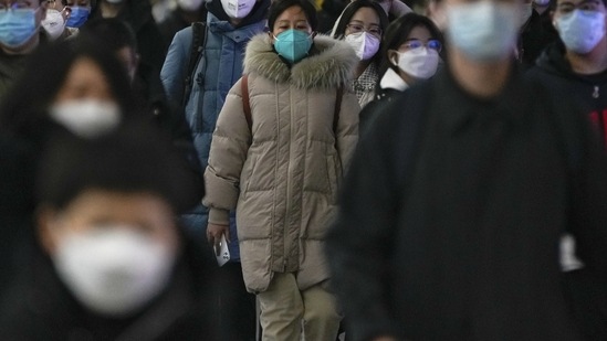 Unemployment In China: Masked commuters walk through a walkway in between two subway stations as they head to work. (AP)