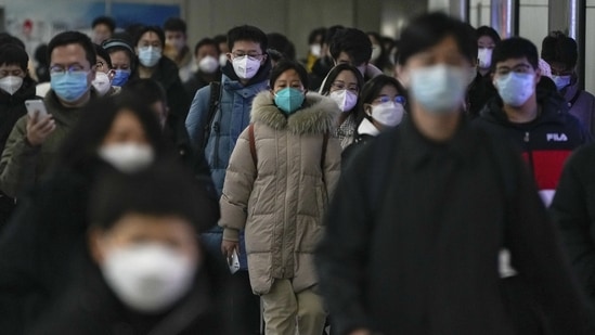 Covid In China: Masked commuters walk through a walkway in between two subway stations as they head to work.(AP)