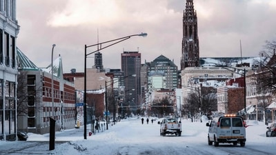 Utility trucks from the National Grid company are seen driving down the snow-covered Main Street in Buffalo, on December 25. US President Joe Biden issued a federal emergency declaration for the state of New York on December 26 night, authorizing US government assistance to bolster state and local recovery efforts. (Joed Viera / AFP)