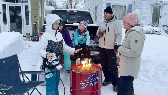 A group of neighbors are seen around a fire pit on Culver Road after clearing snow in Buffalo, on December 26. About 60 per cent of the US population faced some sort of winter weather advisory or warning, and temperatures plummeted drastically below normal from east of the Rocky Mountains to the Appalachians, AP reported.(Carolyn Thompson / AP)