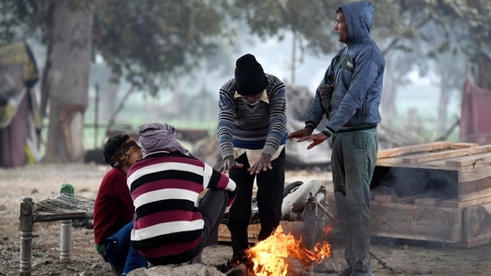 People gather around a bonfire to keep themselves warm on a cold winter morning in New Delhi.(ANI)