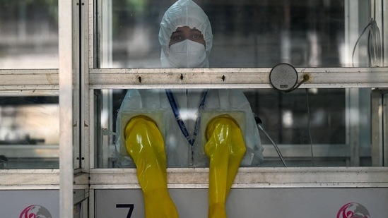 A health worker wearing personal protective equipment (PPE) stands inside a swab collection booth to check preparation of Covid-19 test facilities at a hospital in Mumbai. A health worker wearing personal protective equipment (PPE) stands inside a swab collection booth to check preparation of Covid-19 test facilities at a hospital in Mumbai.