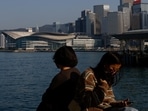 People wearing face masks sit by the sea during the coronavirus disease (Covid-19) pandemic in Hong Kong, China, December 28, 2022. China to finally lift Covid-19 travel restrictions after 3 years of coronavirus lockdown 