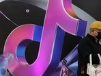A man stands near a giant sign of Chinese company ByteDance's app TikTok. REUTERS/Tingshu Wang/File Photo