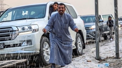 Kuwait Rain-Hailstorm: People inspect hail particles lying on the side of a road after a storm in the Umm al-Haiman district. (AFP) Kuwait Rain-Hailstorm: People inspect hail particles lying on the side of a road after a storm in the Umm al-Haiman district. (AFP)