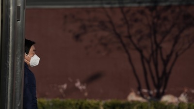 Covid In Japan, Hong Kong, Taiwan: A resident wears a mask as he stands near the shadow of a tree. (AP) Covid In Japan, Hong Kong, Taiwan: A resident wears a mask as he stands near the shadow of a tree. (AP)