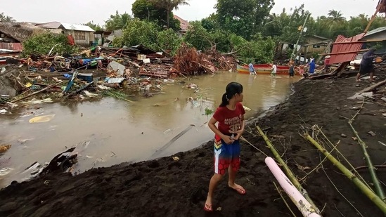 A young girl seen next to damaged houses in Oroquieta City, Misamis Occidental, on December 27. Some residents in the province were seen hanging on to floaters as coast guard rescuers pulled them across chest-deep flood using a rope, AP reported. (Angelica Villarta / AFP)