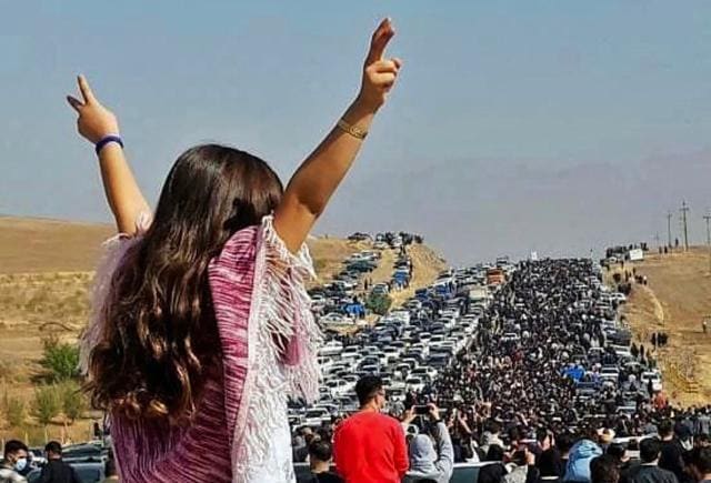 This UGC image posted on Twitter reportedly on October 26, 2022 shows an unveiled woman standing on top of a vehicle as thousands make their way towards Aichi cemetery in Saqez, Mahsa Amini's home town in the western Iranian province of Kurdistan, to mark 40 days since her death, defying heightened security measures as part of a bloody crackdown on women-led protests. A wave of unrest has rocked Iran since 22-year-old Amini died on September 16 following her arrest by the morality police in Tehran for allegedly breaching the country's strict rules on hijab headscarves and modest clothing. (AFP)