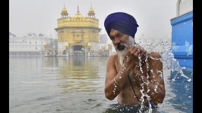 A devotee braving the chill to take a dip at Golden Temple in Amritsar on the birth anniversary of the 10th Sikh Guru, Guru Gobind Singh, on Thursday. (Sameer Sehgal/HT)