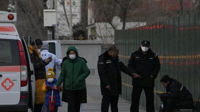 Chinese police personnel check on a man who appears unwell and resting on top of his luggages on the street of Beijing, on Friday. (AP) Chinese police personnel check on a man who appears unwell and resting on top of his luggages on the street of Beijing, on Friday. (AP)
