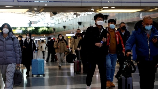 Covid Surge In China: Travellers walk with their luggage at Beijing Capital International Airport.(Reuters)