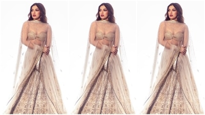 While the golden-coloured blouse features spaghetti straps, a deep sweetheart neckline, an infinity hem design and a fitted bust, the off-white lehenga has intricate embroidery work, sequin adornments, and an A-line layered ghera. She completed the outfit with a see-through zari dupatta - adorned with a gota patti border and embellishments - draped on the shoulders. (Instagram) While the golden-coloured blouse features spaghetti straps, a deep sweetheart neckline, an infinity hem design and a fitted bust, the off-white lehenga has intricate embroidery work, sequin adornments, and an A-line layered ghera. She completed the outfit with a see-through zari dupatta - adorned with a gota patti border and embellishments - draped on the shoulders. (Instagram)