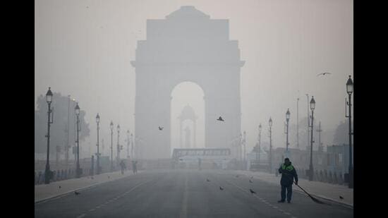 A worker sweeps the road at India Gate amid dense smog. (Photo: Rahul Singh/ANI)