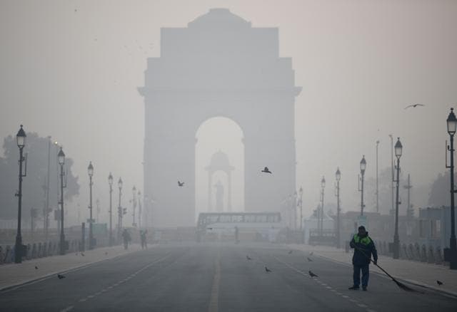A worker sweeps the road at India Gate amid dense smog. (Photo: Rahul Singh/ANI) A worker sweeps the road at India Gate amid dense smog. (Photo: Rahul Singh/ANI)