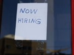 A "Now Hiring" sign is displayed on a storefront. A "Now Hiring" sign is displayed on a storefront.
