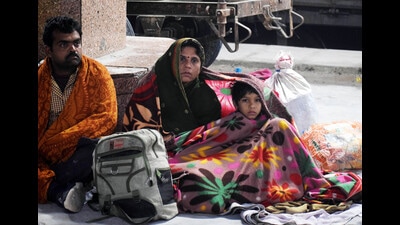 Passengers cover themselves with blankets as they wait to board a train on a cold winter morning, at a railway station, in Prayagraj on Sunday. (ANI Photo)