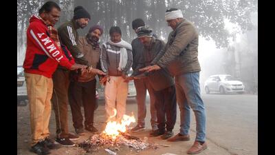 People stand around a bonfire on a foggy winter morning in Amritsar on Monday. (Sameer Sehgal /Hindustan Times)