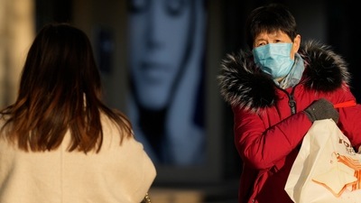 Covid In China: A woman wearing a mask walks on the street in Beijing. (AP) Covid In China: A woman wearing a mask walks on the street in Beijing. (AP)