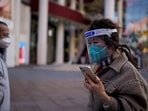 Covid In Shanghai: A woman wearing a protective mask and a face shield walks along in a shopping district in Shanghai, China.