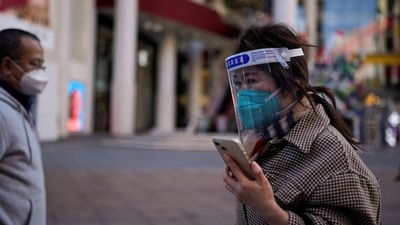 Covid In Shanghai: A woman wearing a protective mask and a face shield walks along in a shopping district in Shanghai, China. (Reuters)
