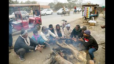 People sit around a bonfire in Patna on Wednesday. (Santosh Kumar/HT Photo)