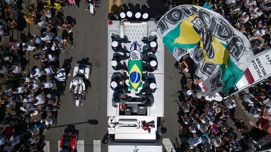 The casket of late Brazilian soccer great Pele is draped in the Brazilian and Santos FC soccer club flags as his remains are transported from Vila Belmiro stadium, where he laid in state, to the cemetery during his funeral procession in Santos, Brazil, Tuesday, Jan. 3, 2023. (AP Photo/Matias Delacroix)(AP)