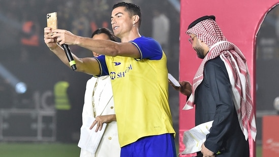 Al-Nassr's new Portuguese forward Cristiano Ronaldo (C) poses for a selfie with the presenters during his unveiling at the Mrsool Park Stadium in the Saudi capital Riyadh on January 3, 2023. (Photo by AFP)(AFP)