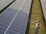 Workers clean photovoltaic panels inside a solar power plant in Gujarat, India. Workers clean photovoltaic panels inside a solar power plant in Gujarat, India.