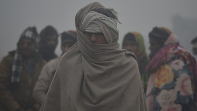Labourer wrapped in a blanket stands on a road during a cold winter morning in Gurugram on Thursday. (ANI)