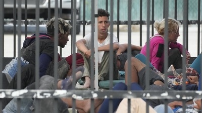 Recently arrived migrants wait in a garage area of the US Customs and Border Protection. (AP) Recently arrived migrants wait in a garage area of the US Customs and Border Protection. (AP)