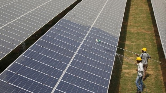 Workers clean photovoltaic panels inside a solar power plant in Gujarat, India. 